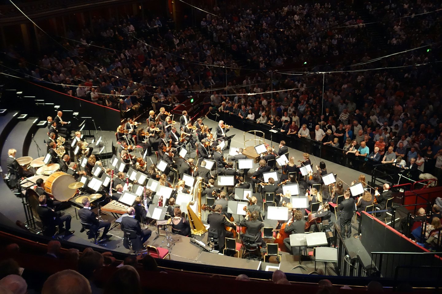 Ein großes Orchester spielt auf der Bühne für ein sitzendes Publikum.